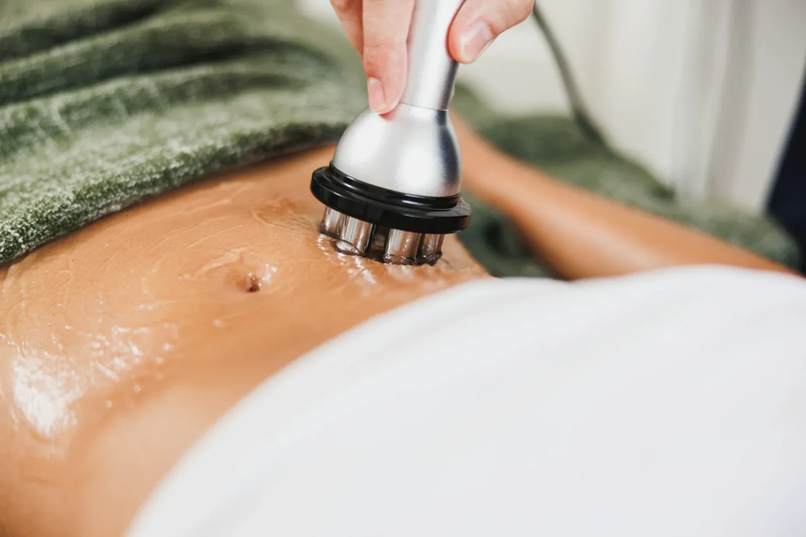 Aparelho estético sendo aplicado com gel no abdômen de uma mulher